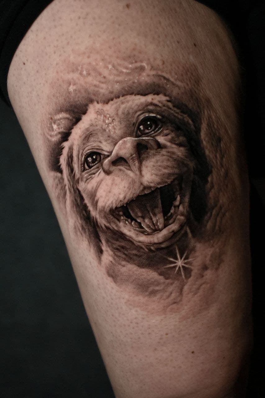 Realistic black and grey tattoo of Falkor the luck dragon smiling joyfully on skin.